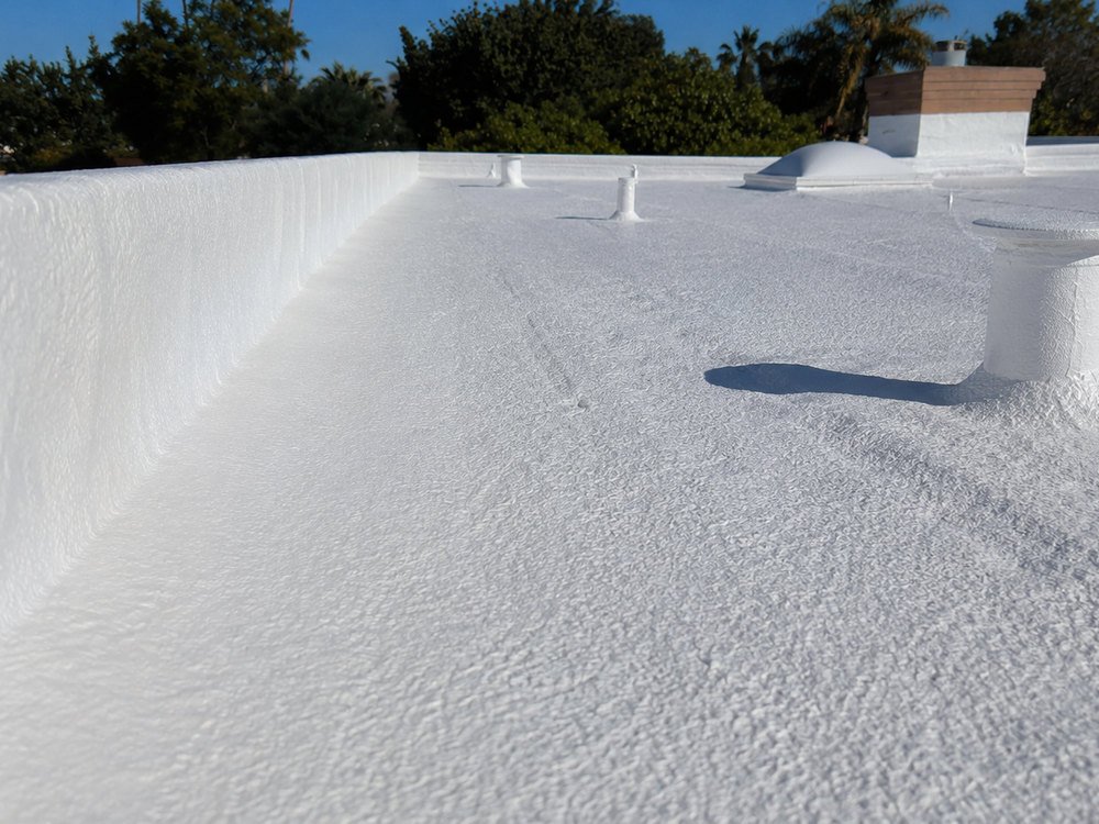Seamless spray foam coating running up a parapet wall